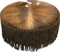 a brown and white cow hide ottoman with fringes on it's sides, viewed from the front