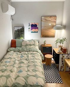 a bed sitting in a bedroom next to a wooden table and two pictures on the wall