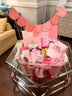 a basket filled with lots of pink items on top of a glass table next to a couch