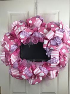 a pink and white polka dot wreath on a door