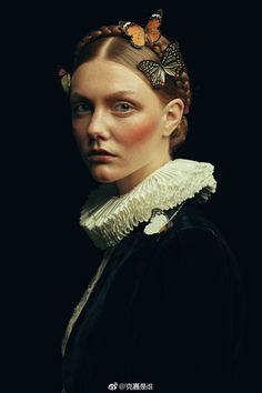 a woman with braids and butterflies on her head, wearing a black dress in the dark