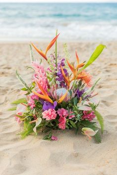 an arrangement of flowers on the sand at the beach