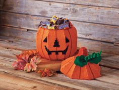 an orange pumpkin with candy in it sitting on top of a wooden table next to leaves