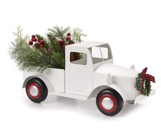 an old fashioned white truck with a christmas tree in it's back end and red rims