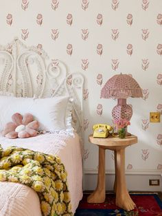 there is a bed with pink flowers on the wall and an umbrella next to it