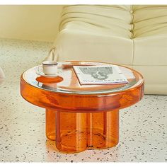 an orange glass coffee table sitting on top of a white couch