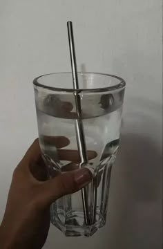 a hand holding a glass with two straws in it