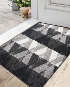 a black and white rug sitting on top of a wooden floor next to a door