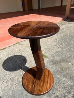 a wooden table sitting on top of a cement floor next to a sidewalk with a building in the background