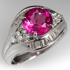 This alluring ring is centered with one (1) round mixed cut natural pink tourmaline set into a four-prong setting. The ring is also accented with twelve (12), prong set, round brilliant cut diamonds and twenty (20), channel set, baguette cut diamonds. The ring measures 12.8mm at the top, rises 7.4mm above the finger, tapering to 2.5mm wide and 1.0mm thick at the base of the shank. This ring is currently a size 6.5. There is a faint natural surface reaching inclusion on the tourmaline and one of the baguette diamonds is chipped but nothing that is distracting. Formal Pink Diamond Ring In Platinum, Formal Pink Sapphire Ring In Platinum, Elegant Pink Diamond Ring In Platinum, Elegant Pink Platinum Rings, Exquisite Pink Diamond Ring With Accent Stones, Pink Ruby Ring With Platinum, Exquisite Pink Diamond Ring With Accents, Classic Pink Sapphire Ring In Platinum, Classic Pink Diamond Ring With Accents