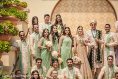 a group of people standing next to each other in front of a wall with potted plants