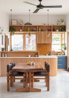 a wooden table and chairs in a room with open shelves on the wall above it