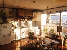 a kitchen with lots of clutter on the floor and windows overlooking cityscape