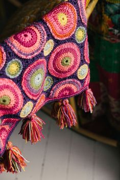 a colorful crocheted blanket with tassels hanging from it's end