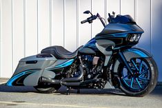 a black and blue motorcycle parked in front of a white garage wall with no one on it