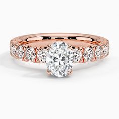 a rose gold engagement ring with an oval cut diamond in the center and side stones