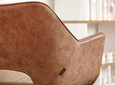 a brown leather chair sitting in front of a book shelf