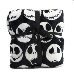 a black and white blanket with jack skellingy faces on it, tied in a bow