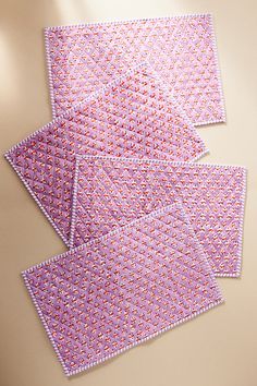 four pieces of pink and purple patterned paper on a beige surface, with small white dots in the middle