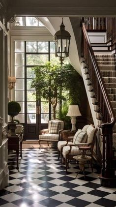 an elegant entry way with black and white checkered flooring, chandelier, chair, table lamp and potted tree