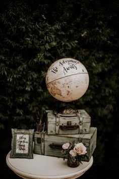 there is a small globe on top of an old suitcase and other items that are sitting on the table