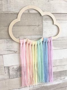 an image of a rainbow cloud with fringes hanging from it's side on a wooden wall