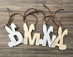 three wooden letters are hanging from strings on a wood surface, with the word bm4 above them