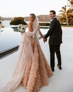 a bride and groom holding hands in front of a pool