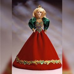 a barbie doll wearing a red dress with gold trimmings and a tiara