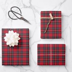 red and black plaid wrapping paper, scissors, and other items laid out on a marble surface