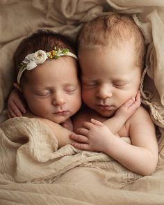 two babies are cuddling together on a blanket