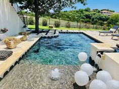 an outdoor swimming pool with clear blue water and white balloons floating in the air next to it