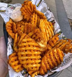 a basket filled with fried food on top of a paper wrapper next to a sidewalk