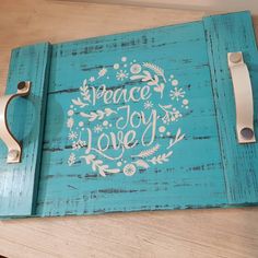 a wooden sign with the words peace joy love written in white on blue paint and flowers