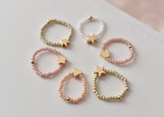 💍 These elegants Miyuki bead  rings are so stunning and chic, customized just for you or for someone you love ❣️ It is the perfect addition to your jewelry collection ❣️  Suitable for  kids (4-10 year old) and adults. ❣️Colours available :  Dusty pink  White  Khaki  ❣️High quality gold plated charms available: star, heart, flower, crown, bear ❣️ You can choose a single item, a set of 3 pcs, or 5 pcs   ❣️These rings are threaded by hand with jewelry elastic thread, so it will fit most sizes and Cute Beaded Rings For Gifts, Cute Spacer Beads For Jewelry Making, Cute Pink Jewelry With Spacer Beads, Cute White Jewelry With Spacer Beads, Heishi Jewelry, Flower Bear, Elastic Rings, Rings Stacking, Heart Crown