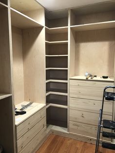 an empty walk - in closet with shelves and drawers on the wall, next to a ladder