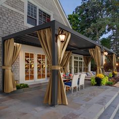 a patio covered in curtains next to a house