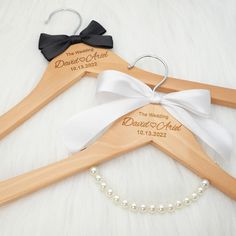 two personalized wooden hangers with white and black bows on them, one is for a wedding dress