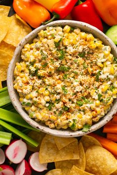 a bowl filled with corn and salsa surrounded by chips, veggies and vegetables