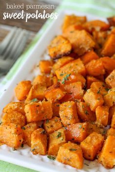 a white plate topped with cut up sweet potatoes and garnished with parsley