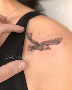 a woman's arm with a bird tattoo on the left side of her shoulder