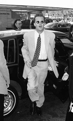 a man in a suit and tie walking out of a car