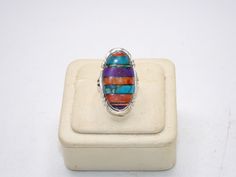 Up for your consideration is this Vintage Sterling Silver Ring. This ring features a gorgeous array of semi precious stones inlaid into the ring. The stones are coral, turquoise, sugilite, and opal doublet. Just stunning! The perimeter of the ring has a saw tooth motif that really ties it together. Pictures best describe. Excellent condition, no damages. The back is marked: "Philippines", "925", with a hallmark on top that I cannot quite make out, but took a photo of.  Ring Size is Approx.: 8.5 Measurement of Ring is Approx.: 1 1/4 inches by 5/8 inches across the front I tested this piece with acid and it is guaranteed to be sterling silver. E-mail me with any questions you may have prior to purchase. Oval Multicolor Multi-stone Rings, Unique Multicolor Cabochon Turquoise Ring, Unique Multicolor Turquoise Cabochon Ring, Multicolor Inlay Rings For Anniversary, Spiritual Multicolor Multi-stone Rings, Anniversary Multicolor Inlay Rings, Unique Oval Multi-stone Turquoise Ring, Unique Multicolor Opal Gemstone Ring, Multicolor Multi-stone Opal Ring