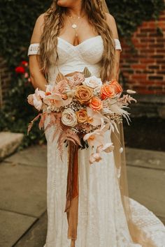 a woman in a wedding dress holding a bridal bouquet with orange and pink flowers