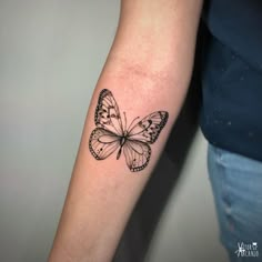 a black and white butterfly tattoo on the arm