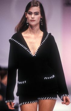 a model walks down the catwalk in a short black dress with white trims