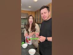 a man and woman standing in front of a kitchen counter with food on the counter