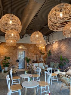 the inside of a restaurant with wicker chairs, tables and lights hanging from the ceiling