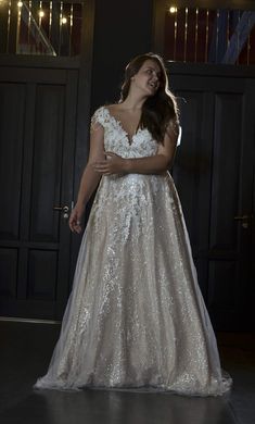 a woman wearing a wedding dress standing in front of a door