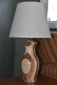 a wooden table with a lamp on top of it and a chair in the background